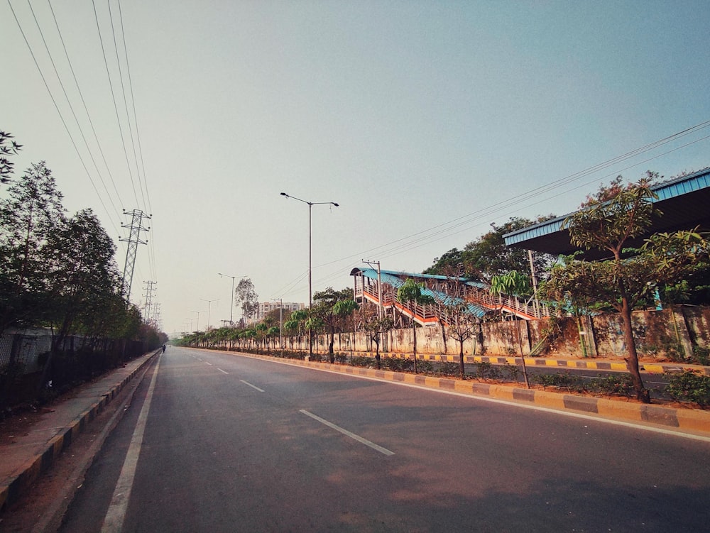 an empty road with a train on the side of it