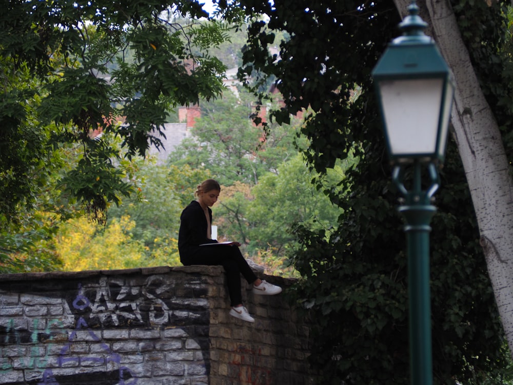 a man sitting on a brick wall reading a book