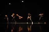 Theater actors in dynamic poses under dramatic stage lighting.
