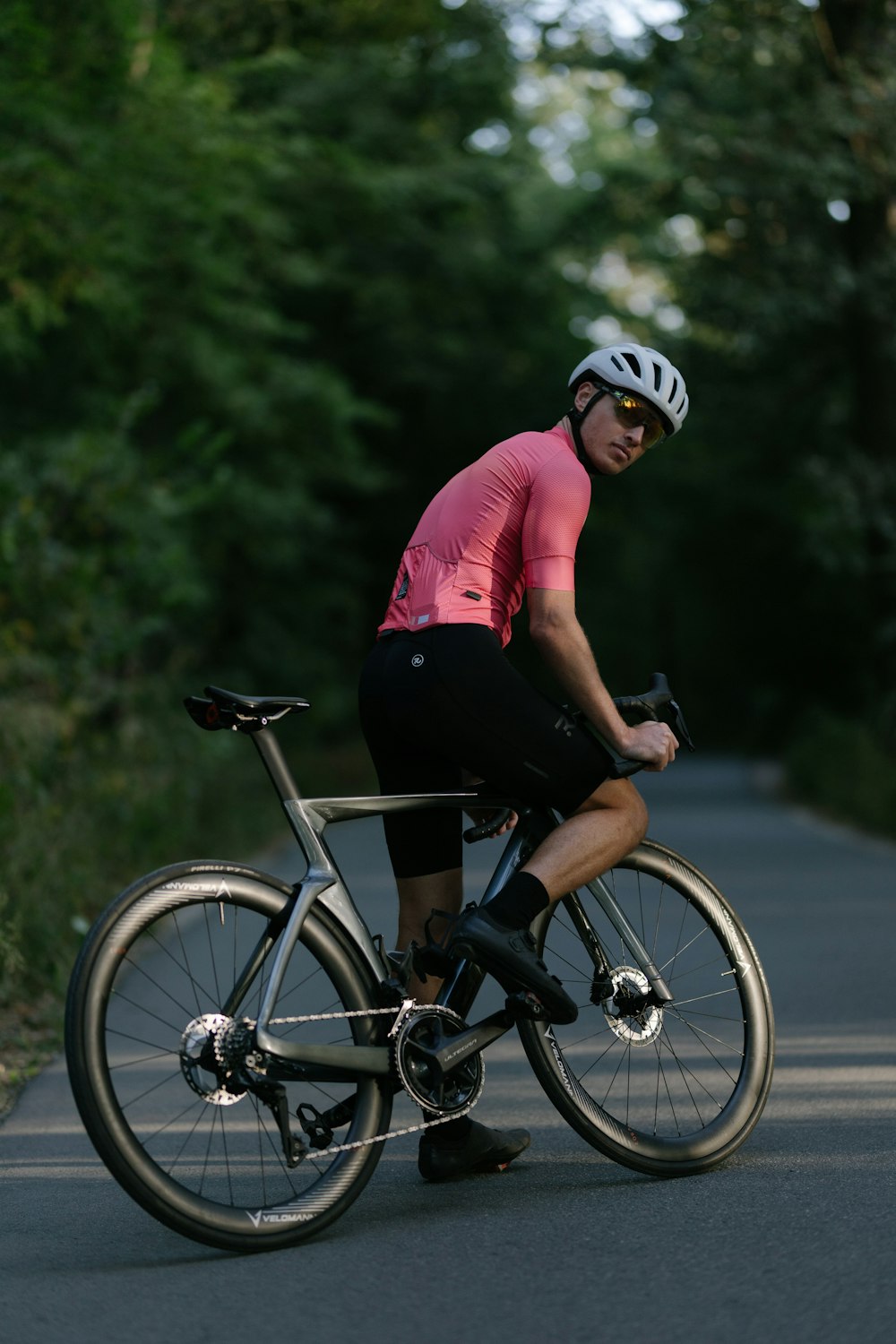 a man riding a bike down a street next to a forest