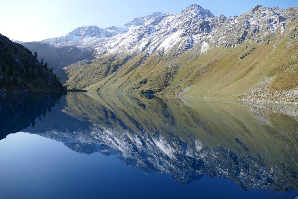 a mountain range is reflected in the still water of a lake