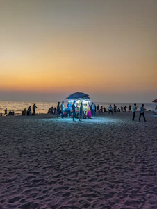 A lively sunset view over Labadi Beach with people enjoying music and local food stalls.