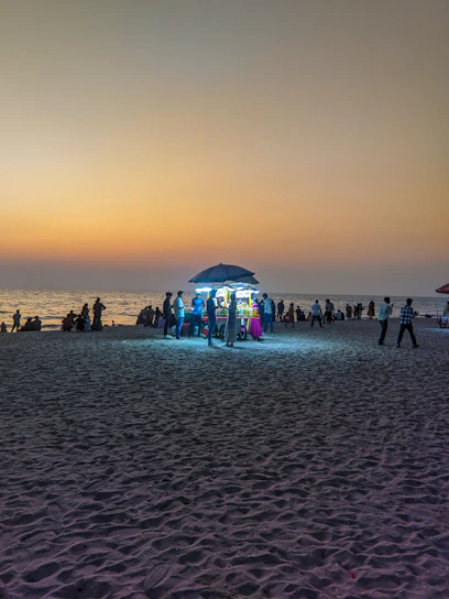 A lively sunset view over Labadi Beach with people enjoying music and local food stalls.