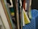 A collection of textbooks and notebooks in various colors with visible spines. Some of the books include subjects like English and sciences. The materials are organized upright in a blue plastic basket.