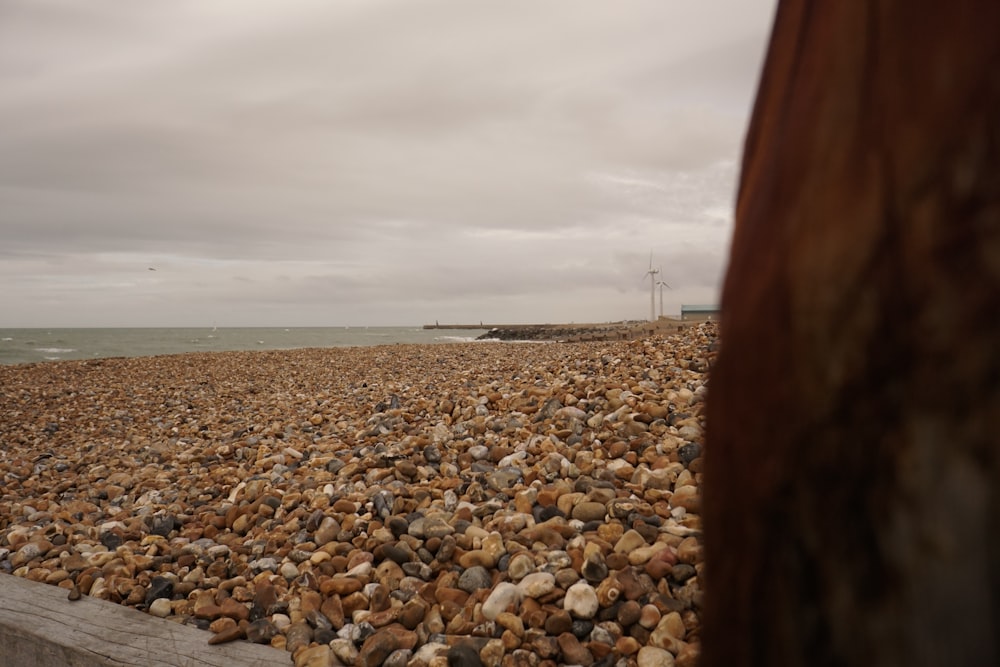 a view of a rocky beach from behind a wooden post