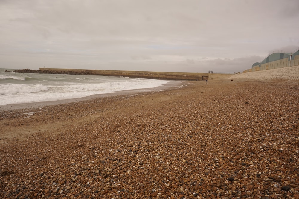 a sandy beach next to the ocean under a cloudy sky