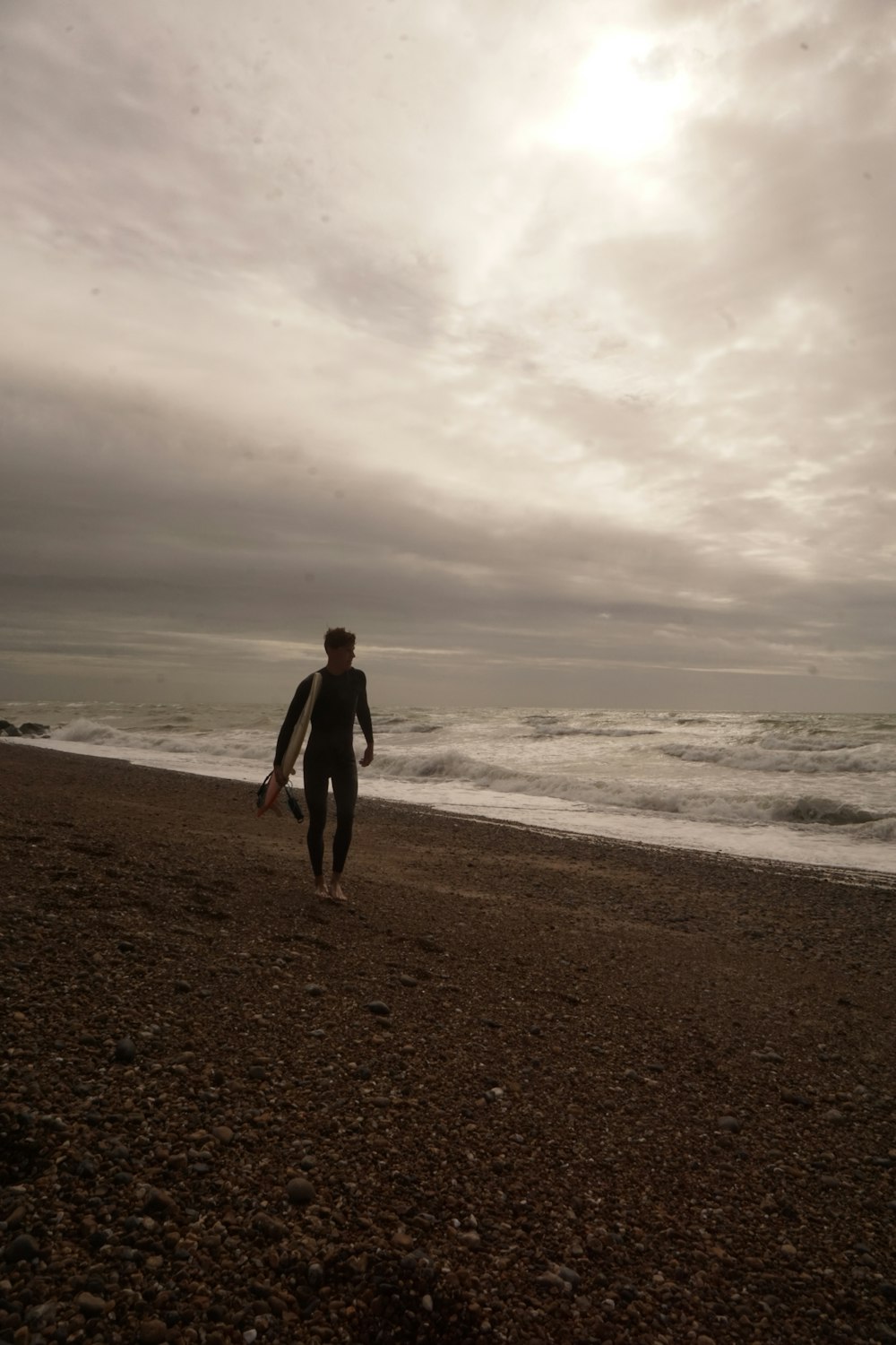 a man walking on a beach with a surfboard
