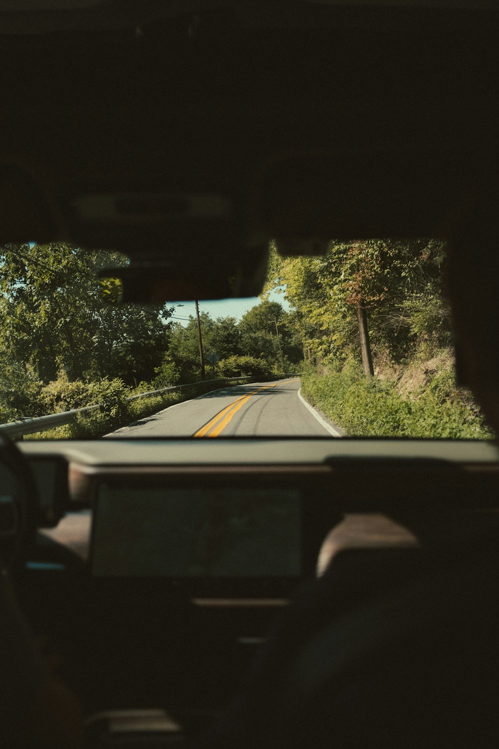 a view from inside a car of a road and trees