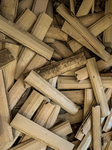 Stack of various wooden planks and beams in a warehouse setting.