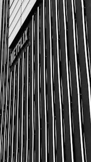 A black and white vertical striped wall features a sign with the word 'Netflix'. The stripes create a striking pattern and the sign is placed at an angle, adding depth to the image.