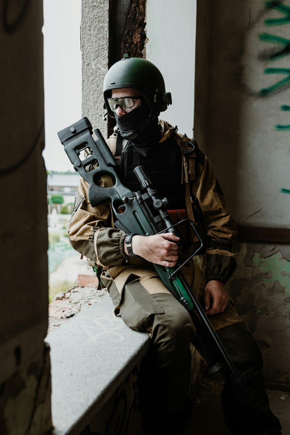 a man sitting on a ledge holding a machine gun