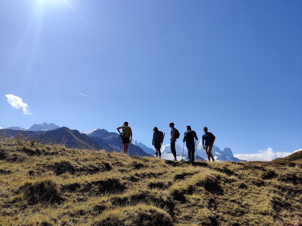 a group of people standing on top of a grass covered hillside