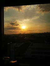 A cityscape view from a hotel window at sunset.