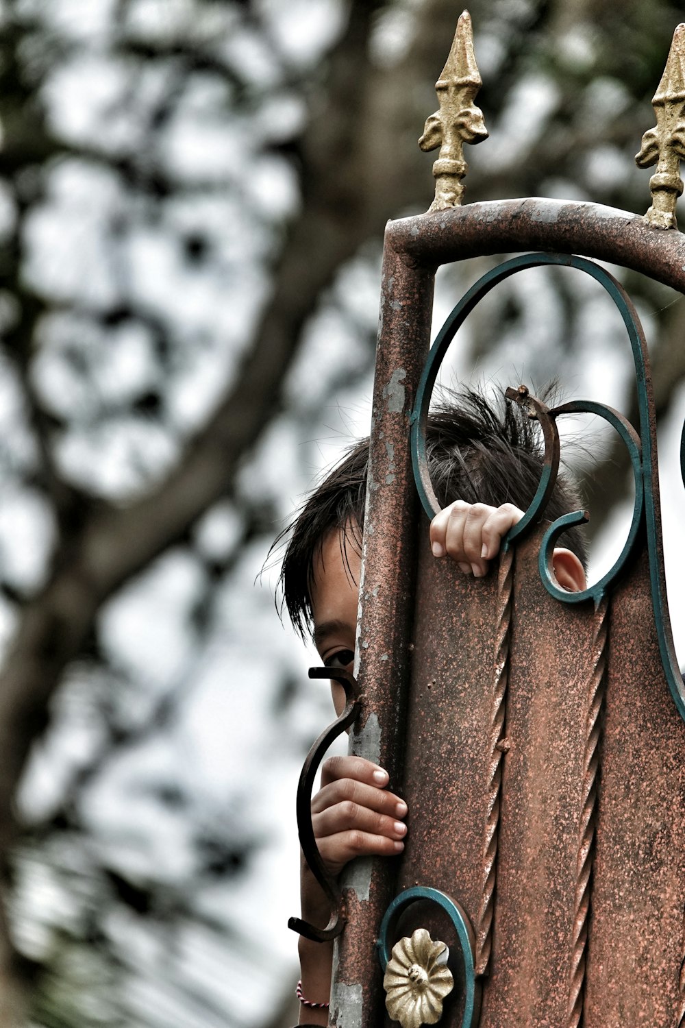 a young boy is peeking out from behind a gate