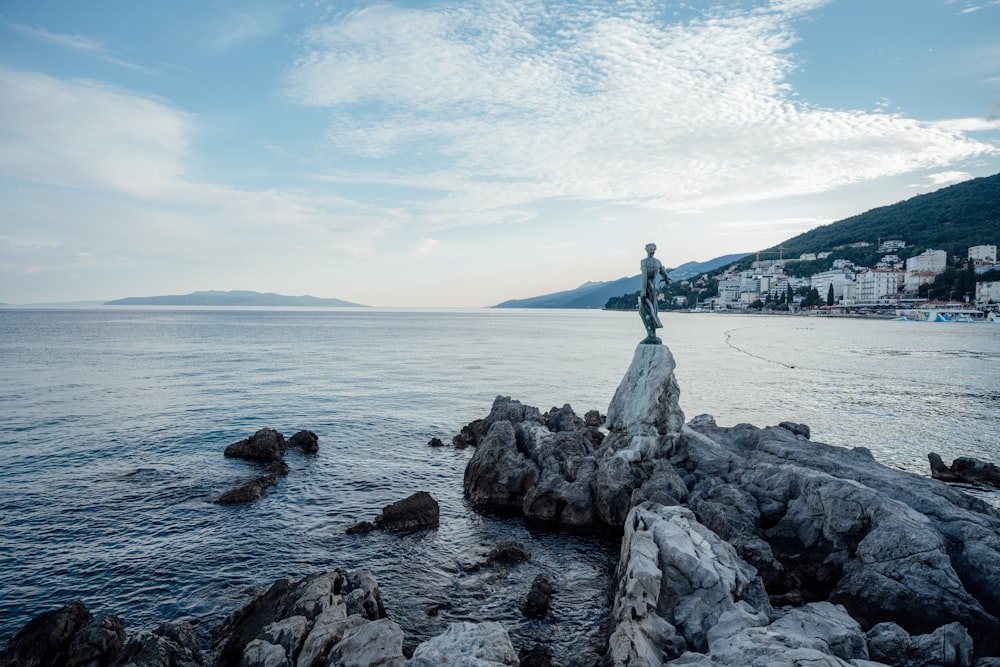 a statue on top of a rock near the ocean