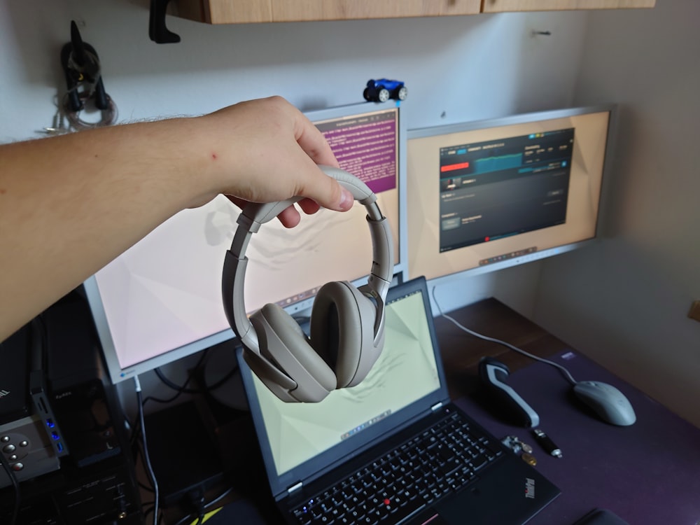 a person is holding a headset over a laptop