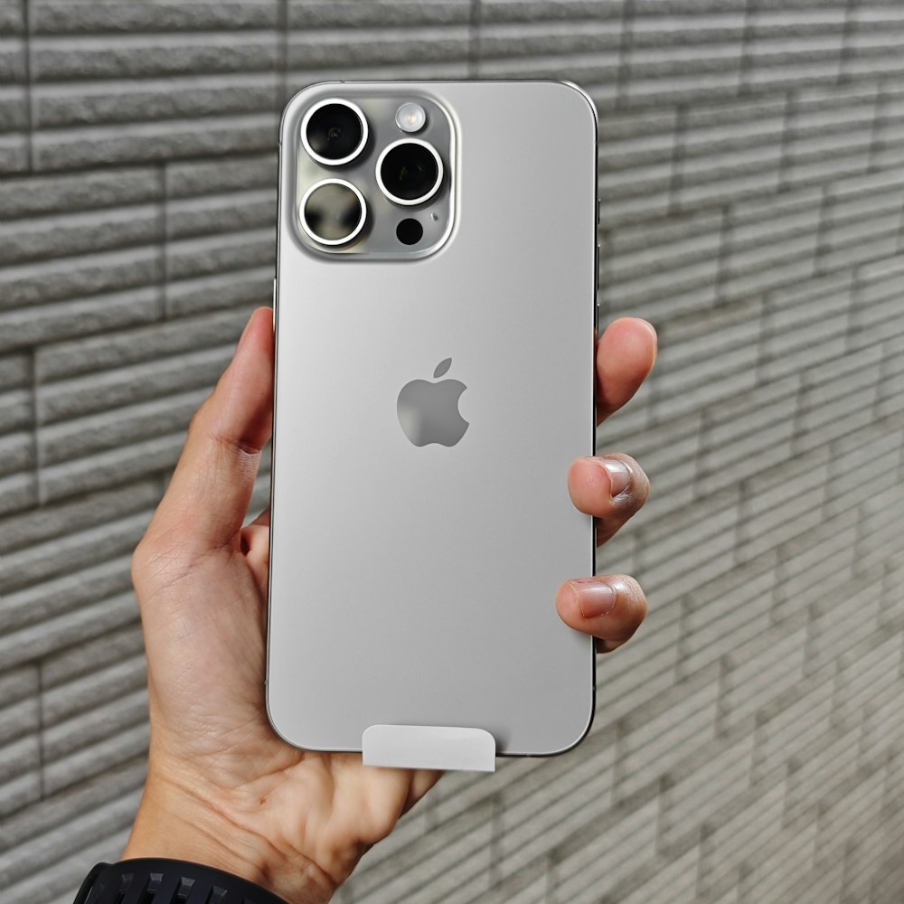 a person holding an iphone in front of a brick wall