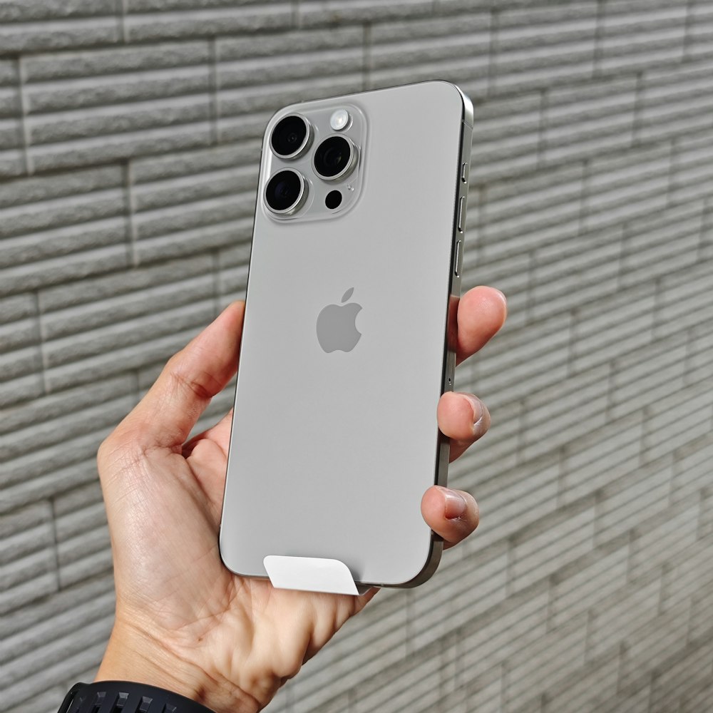 a person holding an iphone in front of a brick wall