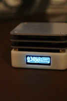 Hands holding a compact volt security unit against a bright background.