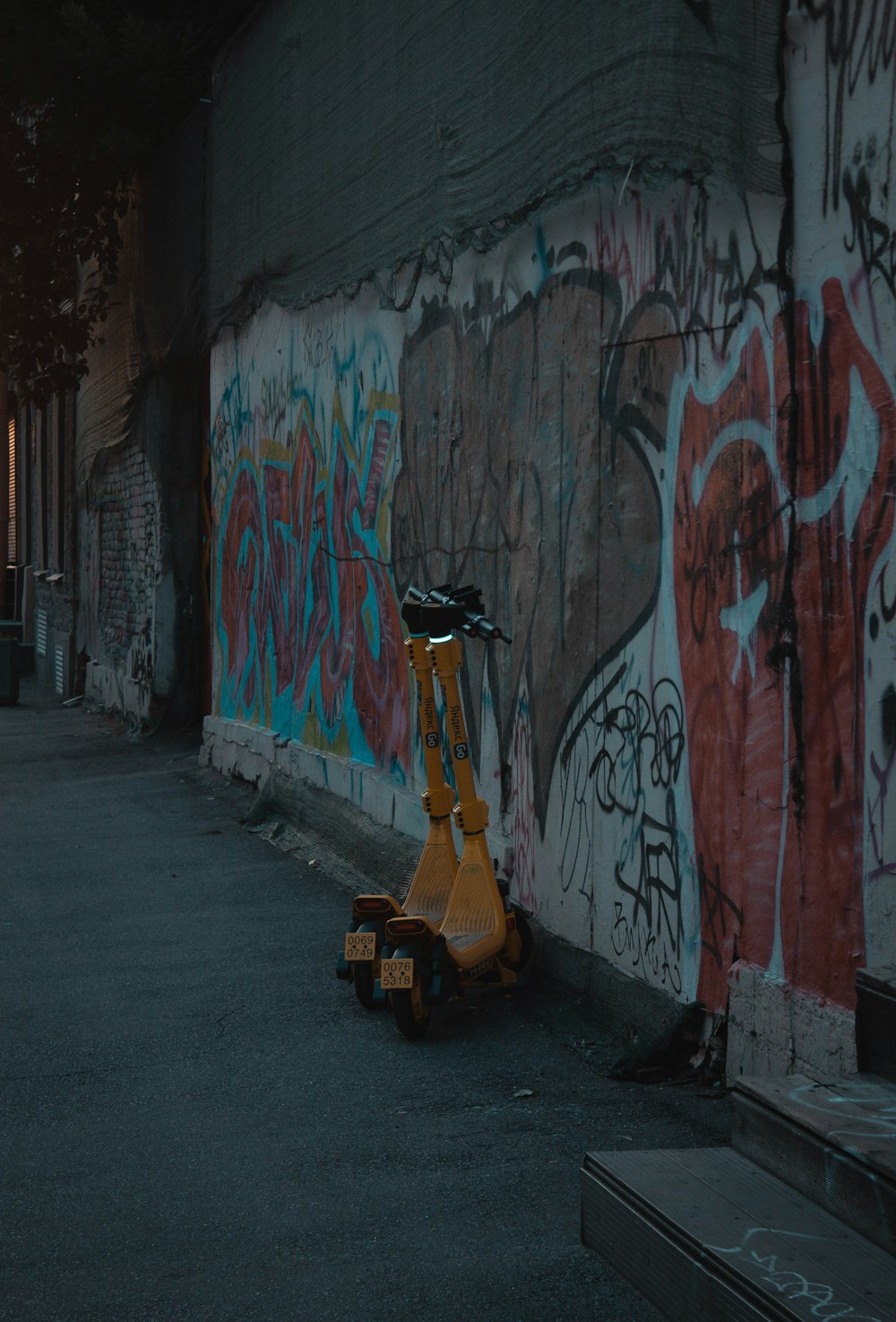 a scooter parked in front of a wall covered in graffiti