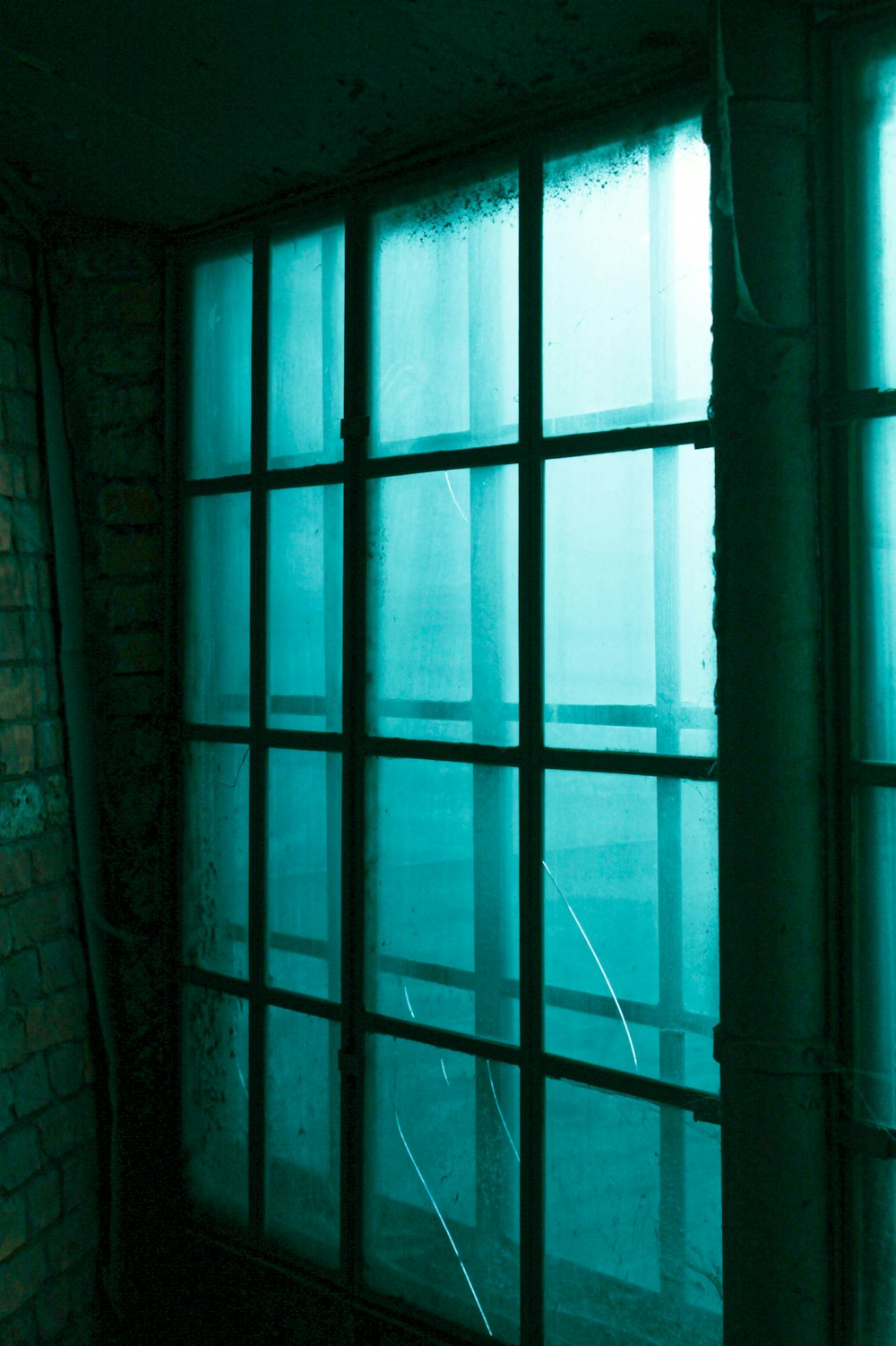 a dark room with a window and a brick wall