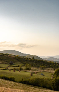 A peaceful landscape of rolling hills and fields surrounding Döğer Kasabası under a clear blue sky