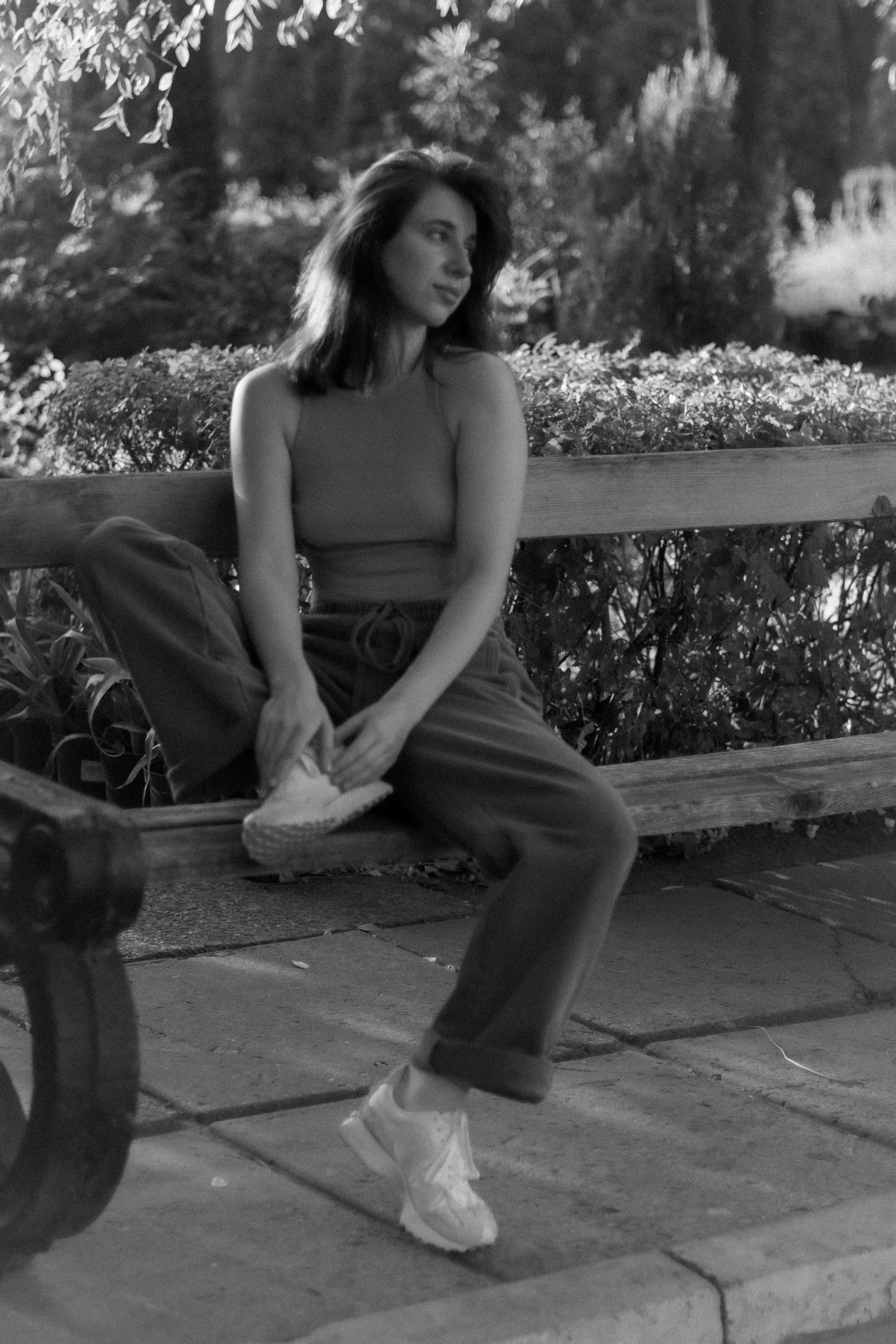 a black and white photo of a woman sitting on a bench
