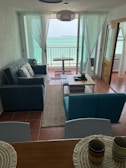 Interior of a bright, modern living room with large windows and sea views.
