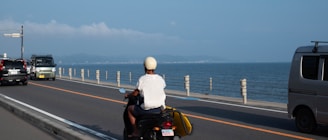 A happy rider cruising along a sunny coastal road on a sleek scooter from Zing Rentals.