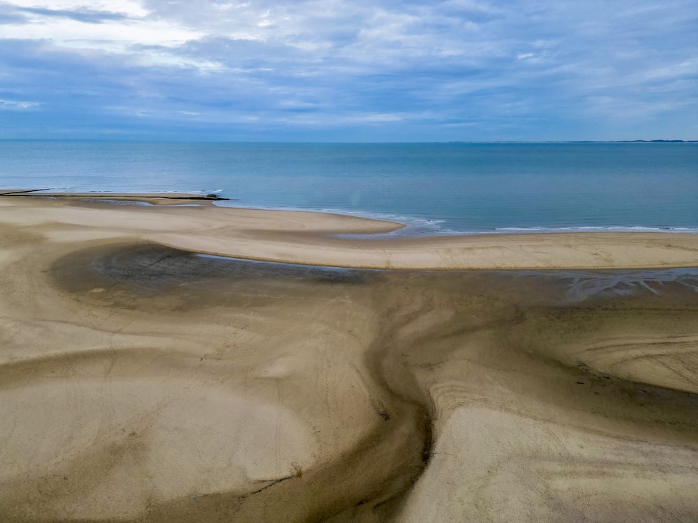 um grande corpo de água sentado ao lado de uma praia de areia