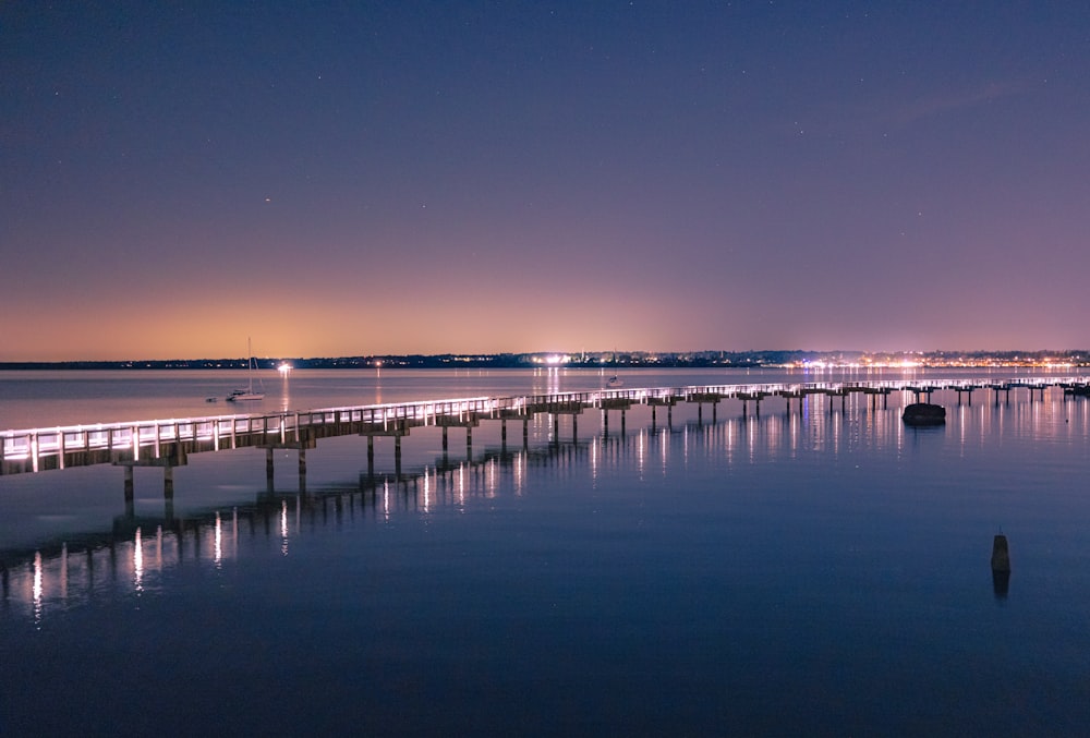 a long pier with lights reflecting off the water