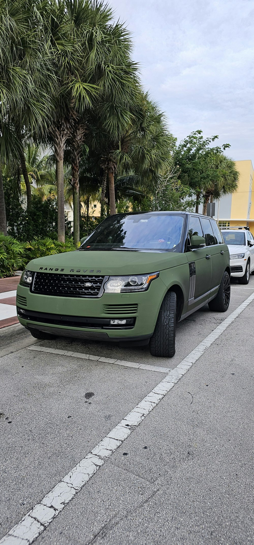 a green range rover parked in a parking lot