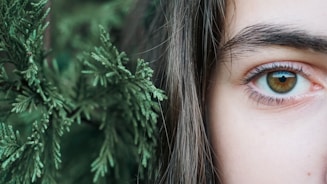 a close up of a person's eye with a plant in the background