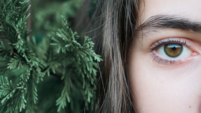 a close up of a person's eye with a plant in the background
