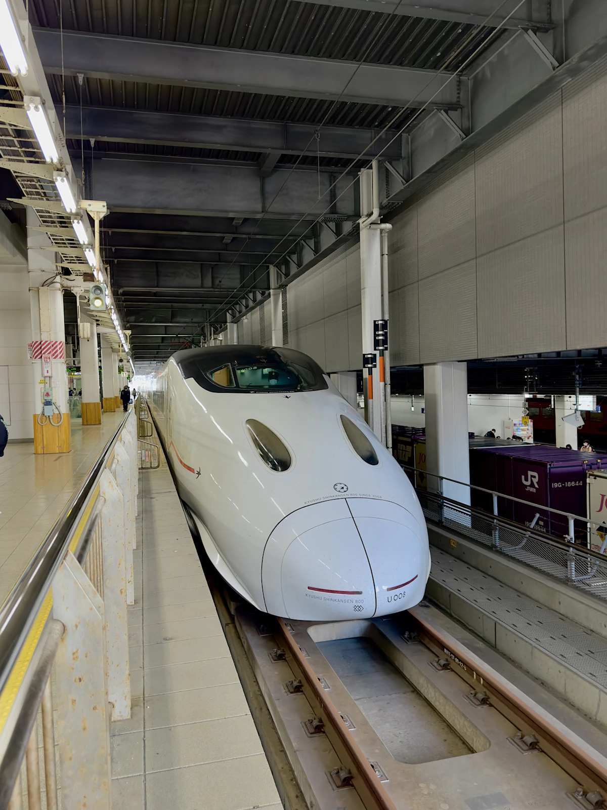 A white Shinkansen stopped at a station platform
