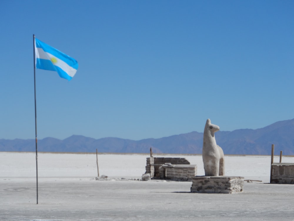 a flag and a statue in the middle of a desert