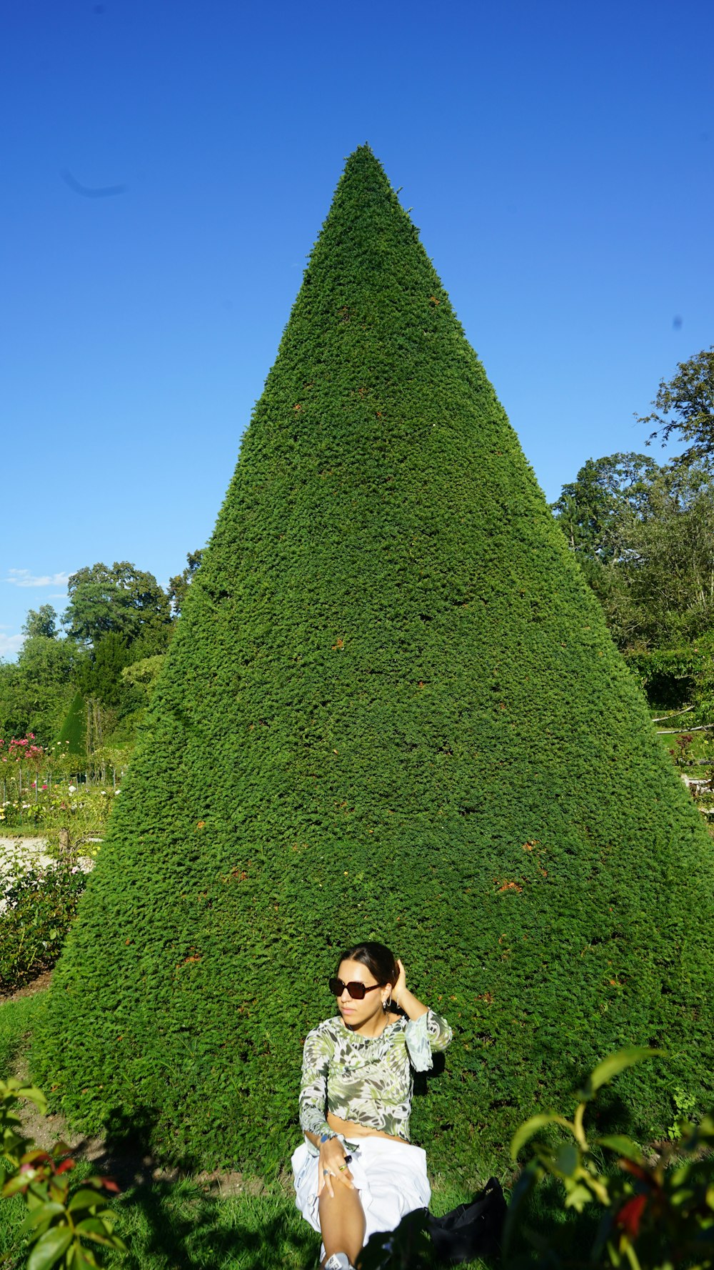 a woman sitting in front of a very tall green cone