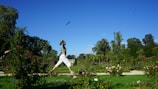 a man is doing yoga in a garden