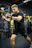 Focused man doing intense cardio on a treadmill in a sleek gym environment with dark theme and vibrant lighting.
