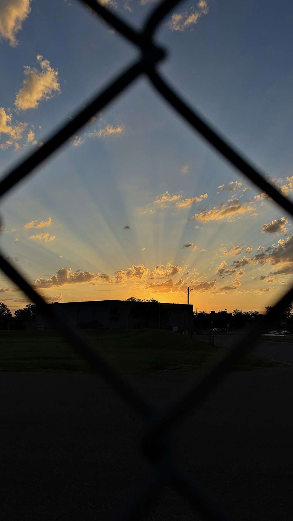 a sunset seen through a chain link fence
