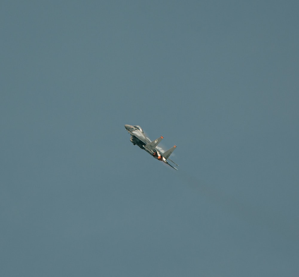 a fighter jet flying through a blue sky