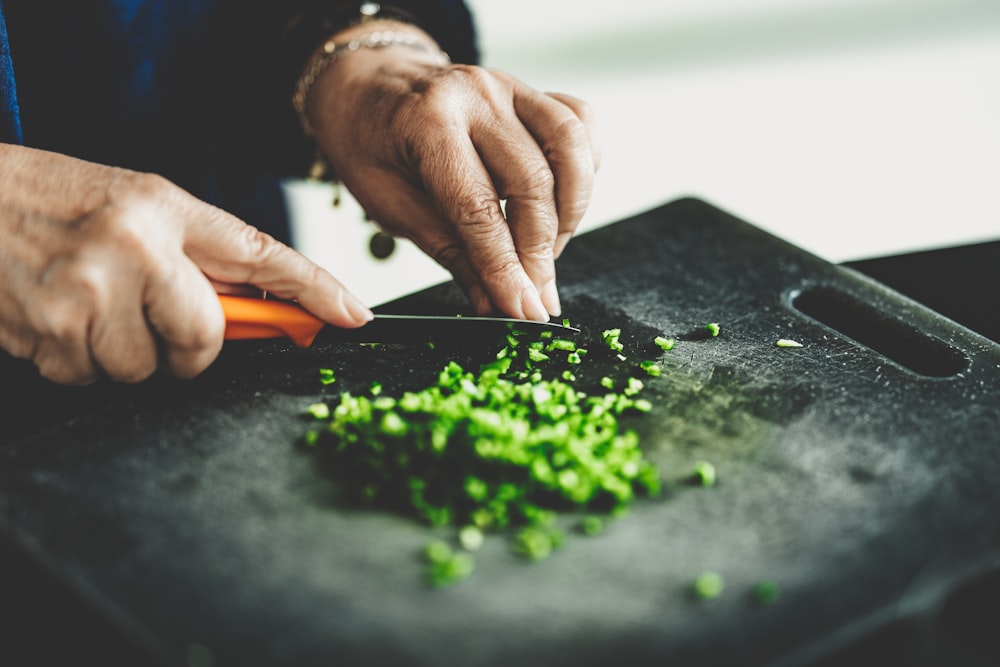 a person chopping green vegetables on a cutting board