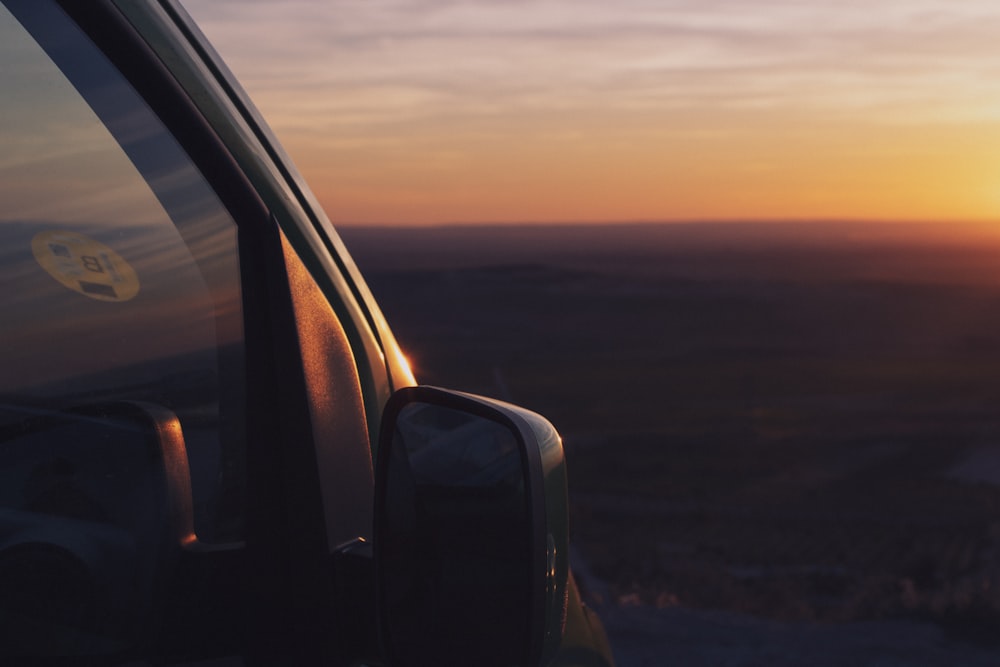 the sun is setting behind a car window