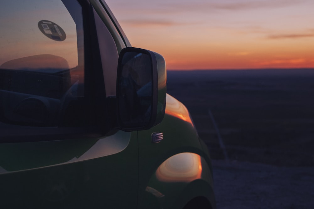 a close up of a car with the sun setting in the background