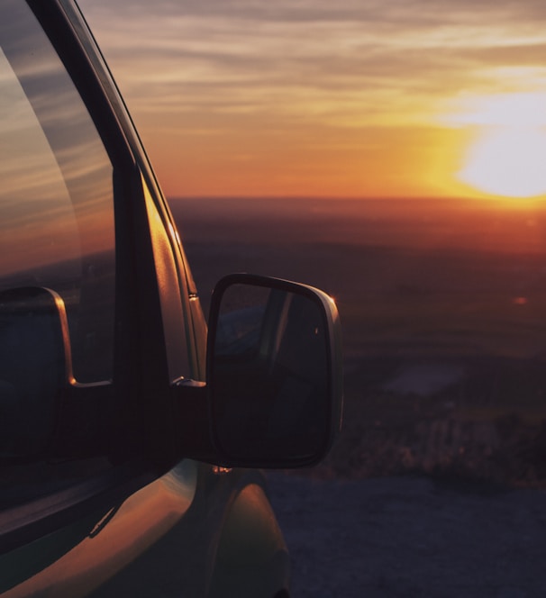 the sun is setting in the distance behind a truck