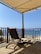 A scenic outdoor patio overlooking the beach with lounge chairs and a wooden deck.