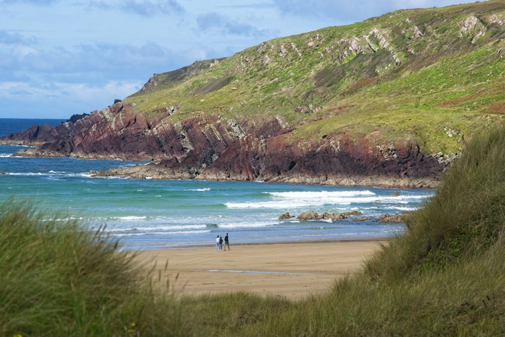 two people walking on a beach near the ocean