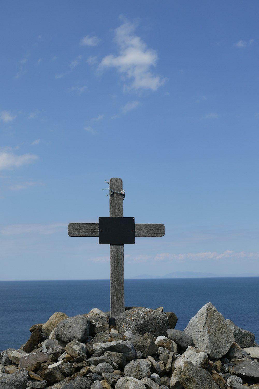 a wooden cross sitting on top of a pile of rocks