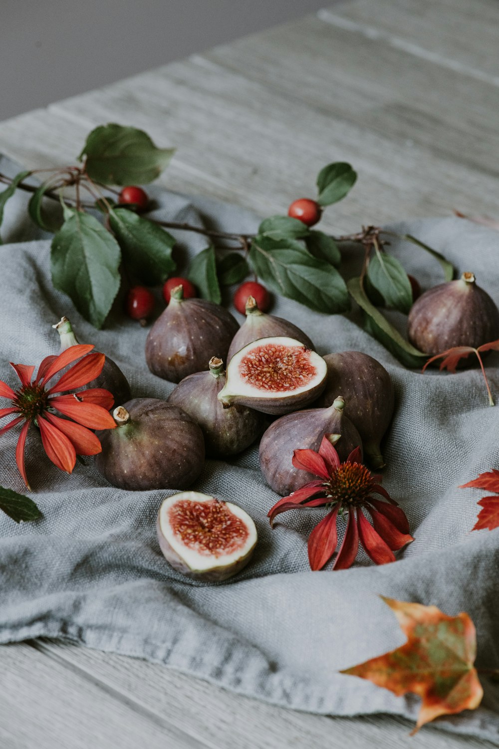 a table topped with figs and flowers on top of a cloth