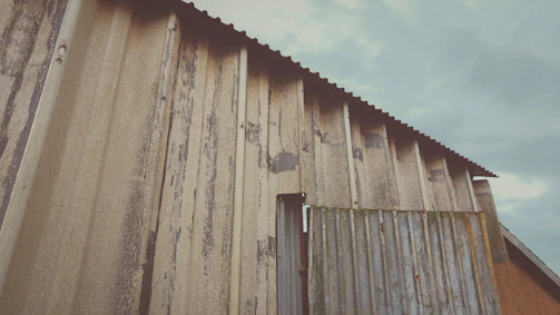 A realistic 4K photo of a metal sheet shed with a blue roof and steel frame structure set against a clear sky in an Indian rural area.